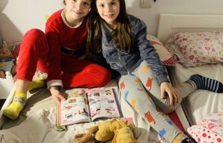 Isabel y su amiga Martina, ilustradora del libro, hojean juntas un catálogo sentadas en la cama.