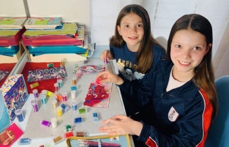 Carolina y una compañera decoran con purpurina unos dibujos de unicornios en el colegio.
