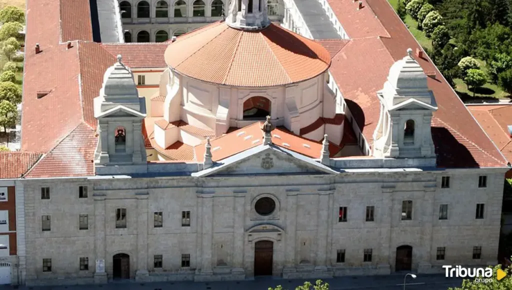 Vista aérea de un edificio histórico de piedra, con cúpula y tejados de teja roja, bajo la marca de agua de Tribuna.