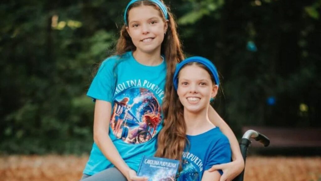 Isabel und Carolina halten in den T-Shirts von Carolina Purpurina das Buch in einem Park.